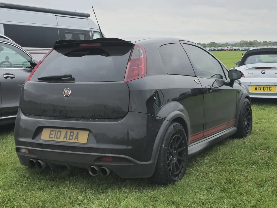 White Abarth Grande Punto with red stripes, front three-quarter view, outdoor