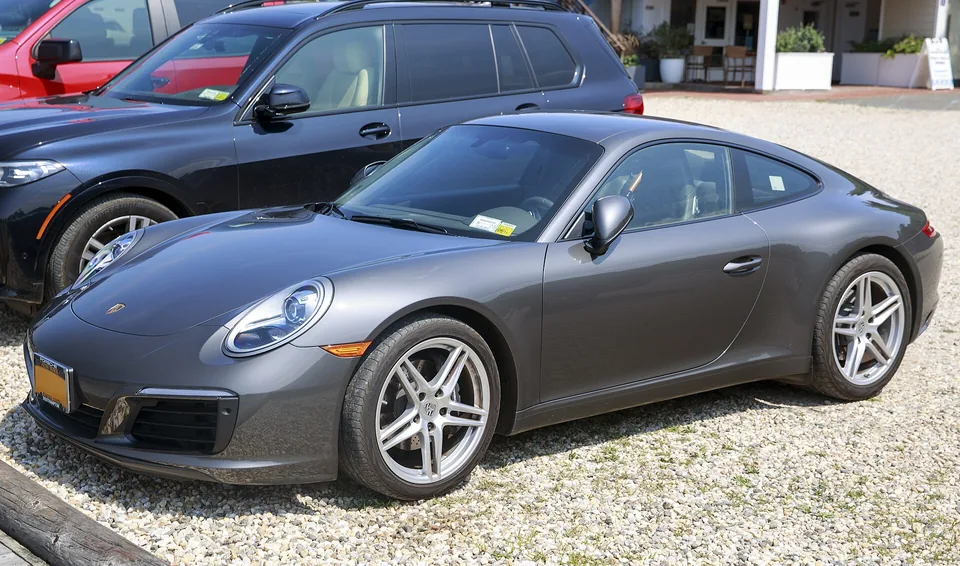 Agate Grey Metallic 2019 Porsche 911 Carrera (991.2) coupé on gravel at a Long Island marina, three-quarter front view