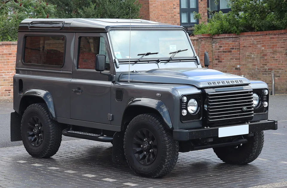 Grey Land Rover Defender 90 XS station wagon parked on a brick forecourt, three-quarter front view