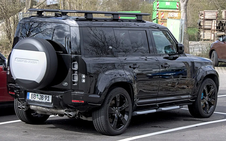 Black Land Rover Defender 110 V8 (L663), rear three-quarter view showing the quad exhausts