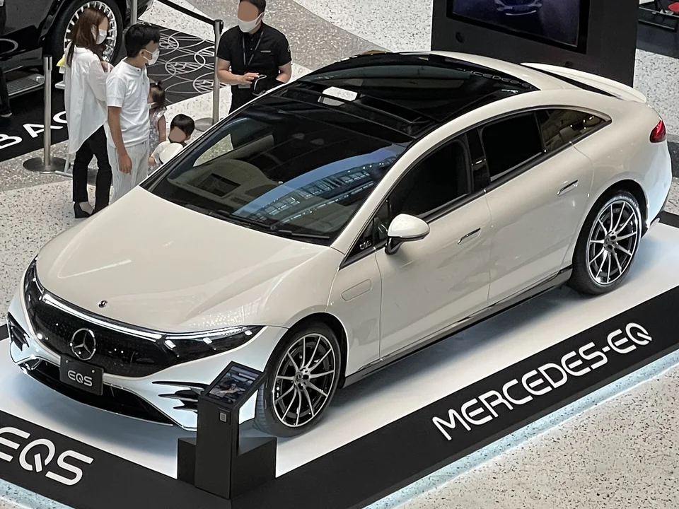 White Mercedes-Benz EQS 450+ (V297) on a Japanese show stand, three-quarter front view