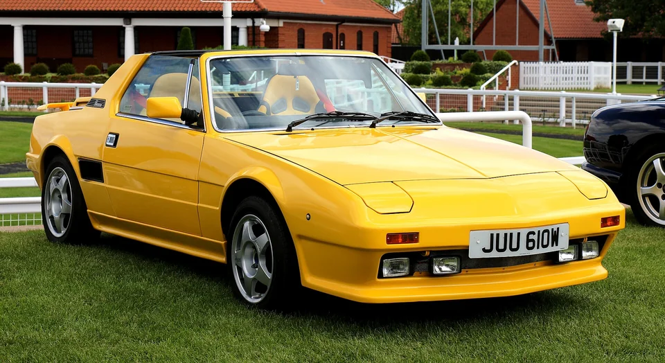 Yellow Fiat X1/9 with the targa roof panel in place, front three-quarter view