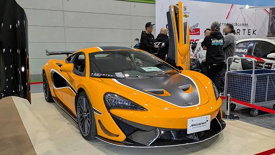 Orange McLaren 620R with doors open, three-quarter front view