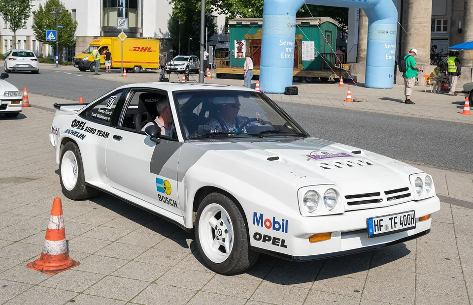 White Opel Manta 400 in period Opel Euro Team rally livery at a classic rally start, three-quarter front view