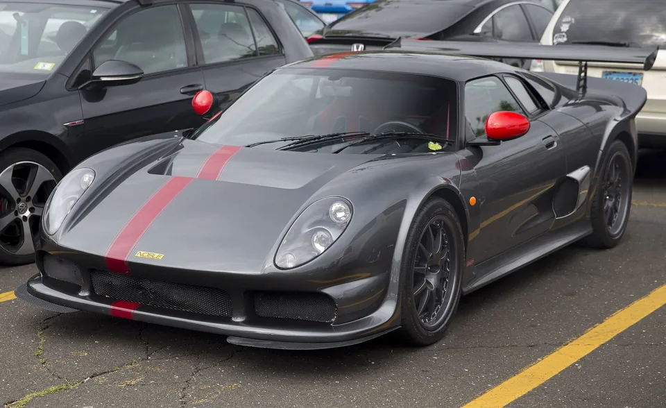 Dark grey Noble M400 with a red stripe, front three-quarter view