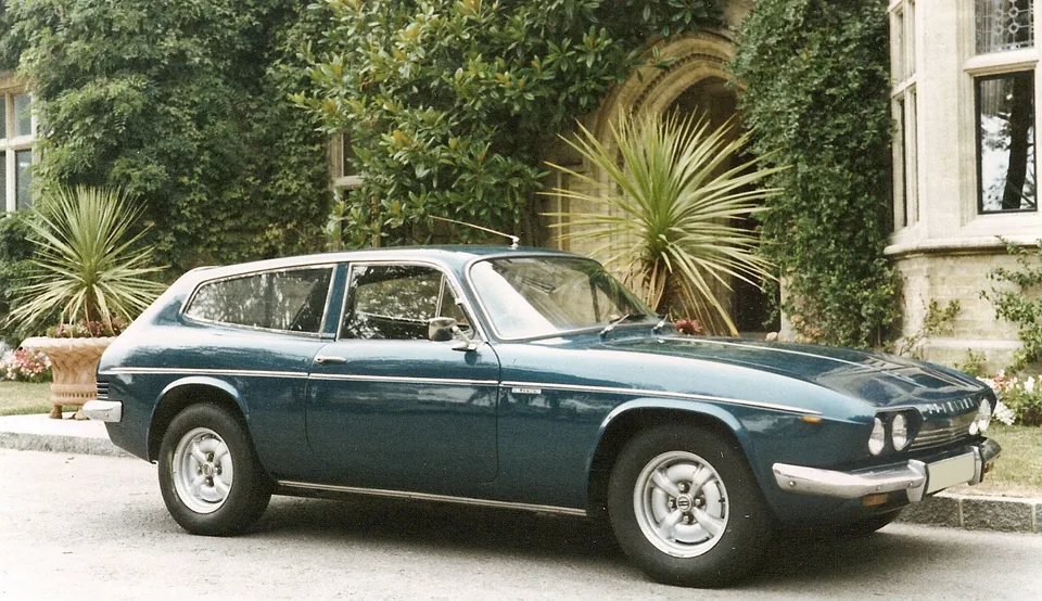 Teal 1971 Reliant Scimitar GTE (SE5) on a gravel drive, three-quarter front view